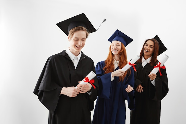 Felices graduados internacionales sonrientes regocijándose con diplomas.