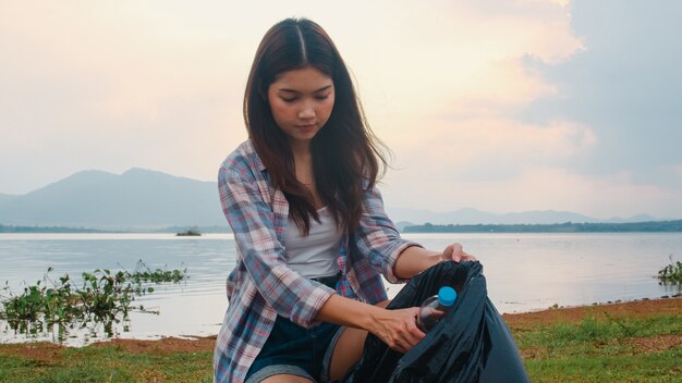 Felices jóvenes activistas de Asia recogiendo residuos plásticos en la playa. Las voluntarias coreanas ayudan a mantener la naturaleza limpia y recoger la basura. Concepto sobre problemas de contaminación de conservación ambiental.