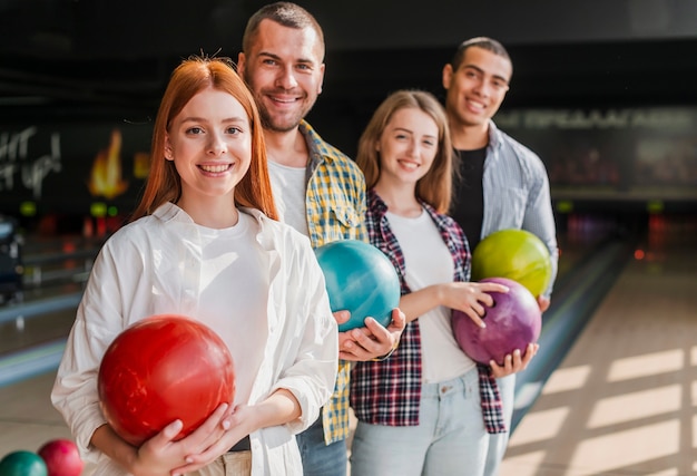 Felices jóvenes amigos con bolas de boliche tiro medio