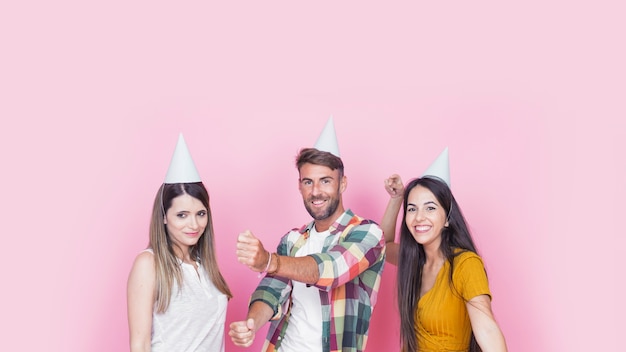 Felices jóvenes amigos divirtiéndose en fondo rosa