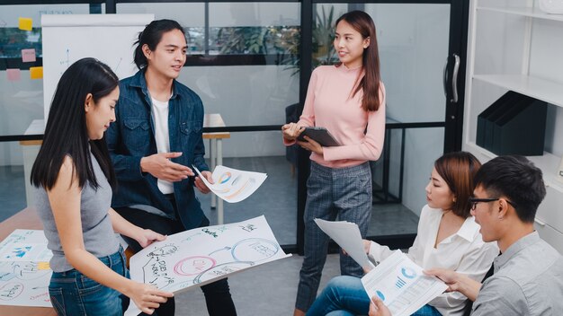 Felices jóvenes empresarios asiáticos y empresarias reunidos para intercambiar ideas