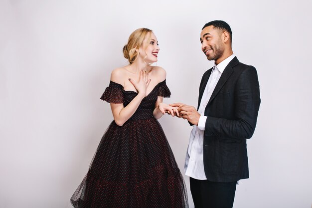 Felices momentos encantadores de linda pareja de chico guapo haciendo propuesta de matrimonio a hermosa joven rubia en vestido de lujo. Expresando felicidad, enamorado, día de San Valentín.