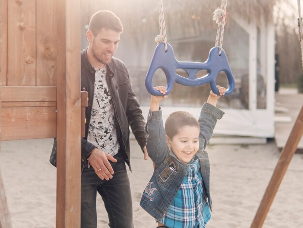 Felices momentos de niño y padre en el patio de recreo