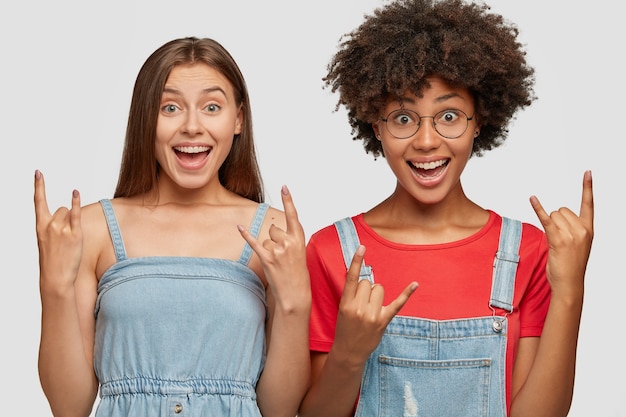 Felices mujeres emotivas hacen gesto de rock n roll