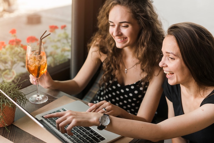 Foto gratuito felices mujeres jóvenes que miran la computadora portátil
