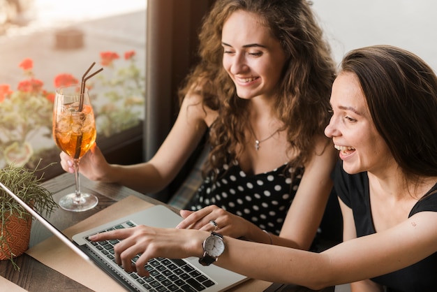 Felices mujeres jóvenes que miran la computadora portátil
