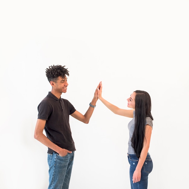 Felices multirraciales amigos masculinos y femeninos que dan alta cinco sobre fondo blanco