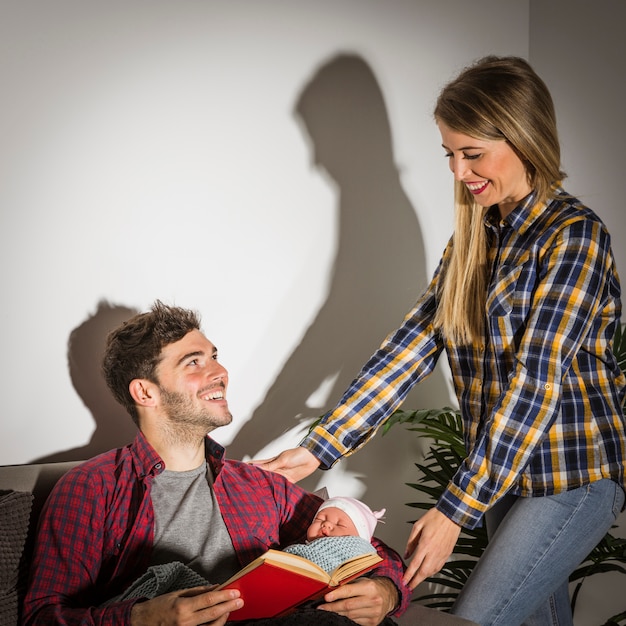 Foto gratuita felices padres con bebe y libro.