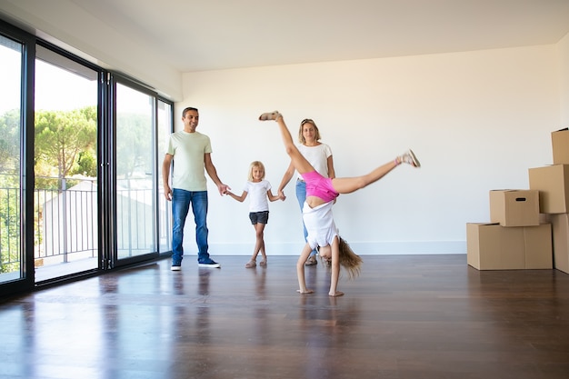 Foto gratuita felices padres e hijas celebrando el estreno de una casa, niña haciendo voltereta