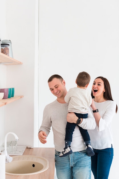 Felices padres con niño en la cocina