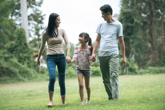 Felices padres y su hija caminando en el parque, concepto de familia feliz.