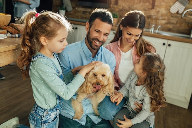 Felices padres y sus hijas disfrutando en casa y divirtiéndose con su perro