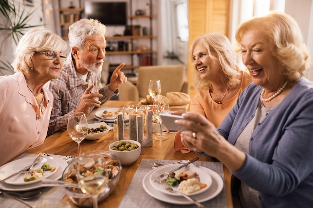 Felices personas maduras comunicándose mientras almuerzan juntos en el comedor de casa