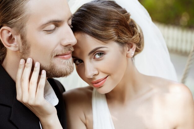 Felices recién casados hermosos en traje y vestido de novia sonriendo, disfrutando.