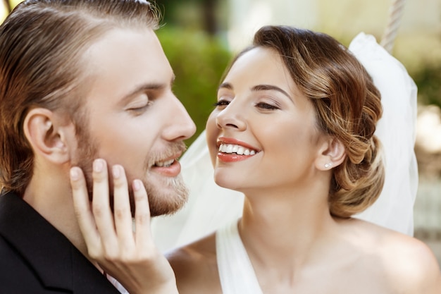 Felices recién casados hermosos en traje y vestido de novia sonriendo, disfrutando.