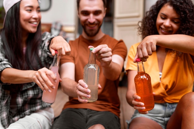 Felices tres amigos abriendo sus bebidas