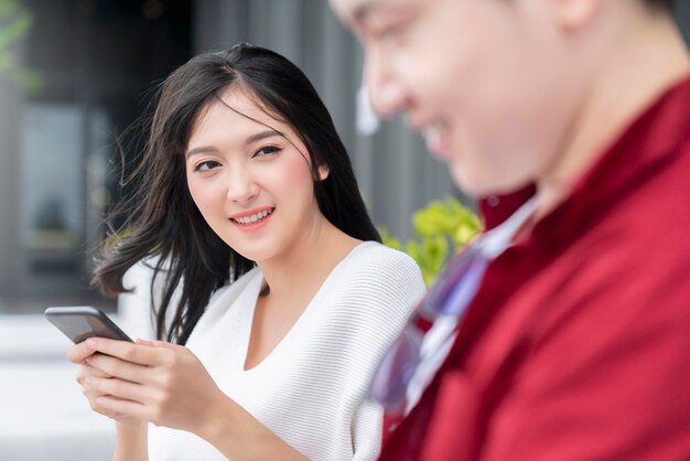 Felicidad alegre pareja asiática joven contacto visual masculino y femenino risa sonrisa juntos diversión conversación relajarse vestido casual encuesta y jardín vacaciones fin de semana resort fondo