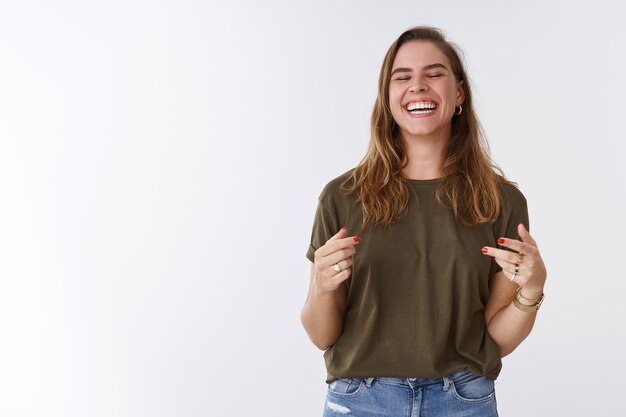 Felicidad, deleite, concepto de bienestar. Atractiva mujer positiva encantadora despreocupada divirtiéndose riendo a carcajadas sinceras ojos cerrados diciendo jaja gesticulando escuchando broma hilarante, riendo entre dientes