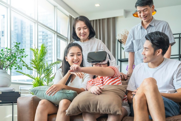 Felicidad familia asiática generación de varias edades disfruta de ver y animar a su hija jugando vr goggle junto con diversión y salió en la sala de estar fondo interior de la casa fin de semana de cuarentena