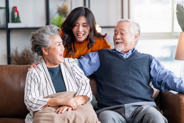 Felicidad familia asiática sincera de hija abrazo abuelo madre más anciano anciano acogedor relajarse en el sofá sofá sorpresa visitando en la sala de estar en casa juntos abrazar alegre familia asiática en casa