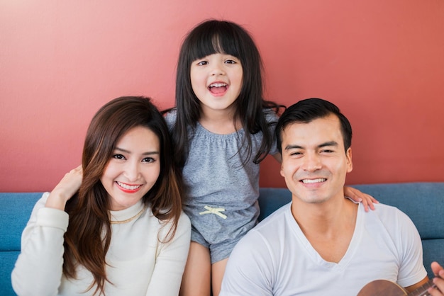 Felicidad familia mujer joven con padres jugar juntos con amor y alegría en el sofá en el concepto de relación de la casa de la sala de estar