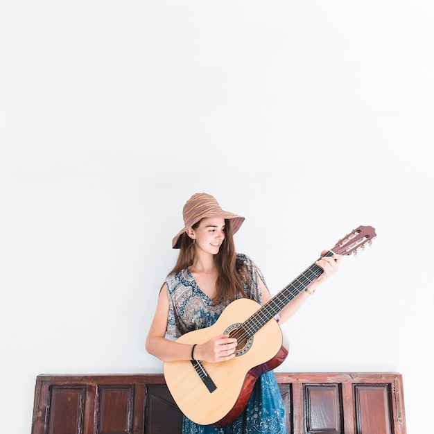 Foto gratuita feliz adolescente tocando la guitarra delante de la pared