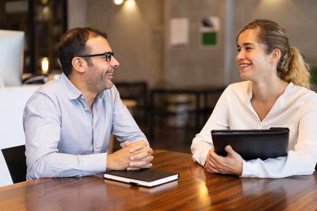 Feliz adulto de mediana edad hablando con una joven cliente.