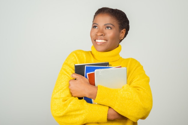 Feliz alegre estudiante abrazando libros