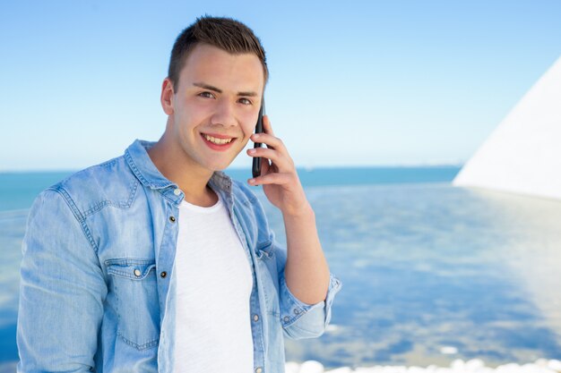 Feliz alegre estudiante chico hablando por teléfono móvil