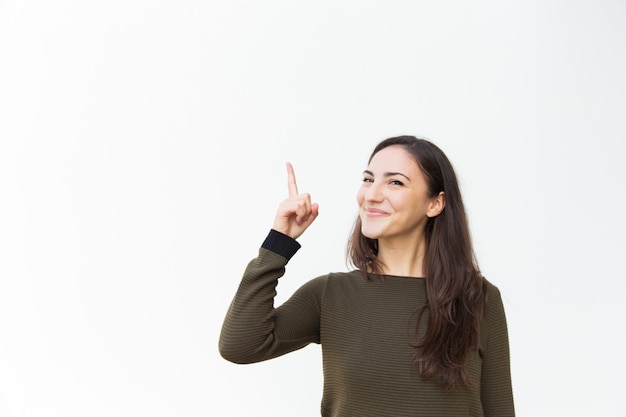 Feliz alegre hermosa mujer apuntando el dedo hacia arriba