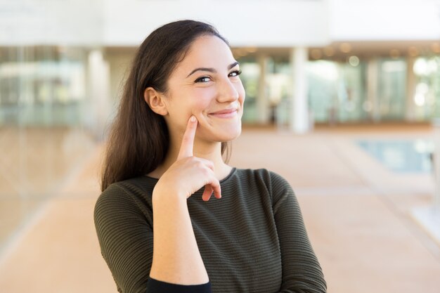 Feliz alegre hermosa mujer tocando la cara con el dedo índice