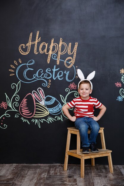 Feliz alegre niño con orejas de conejo y celebrando la Pascua