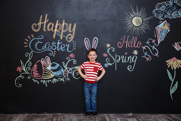 Feliz alegre niño con orejas de conejo y celebrando la Pascua