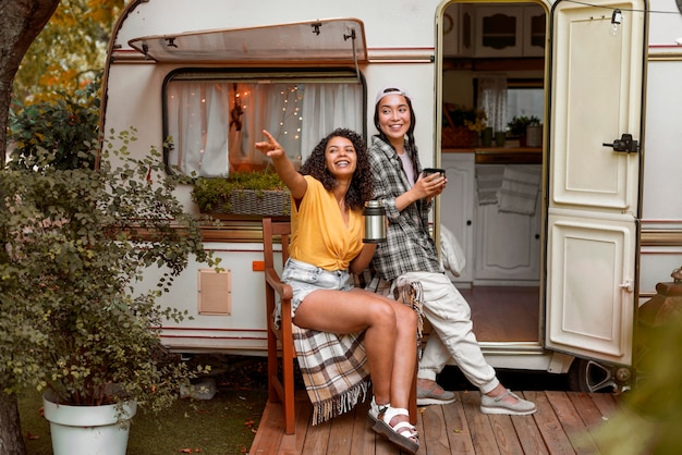 Feliz amigas sentado junto a una autocaravana