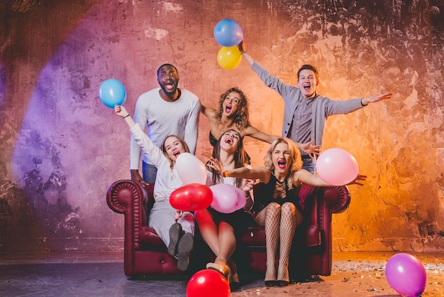 Feliz amigos con globos en el sofá