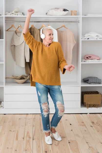 Foto gratuita feliz anciana bailando mientras escucha música en los auriculares