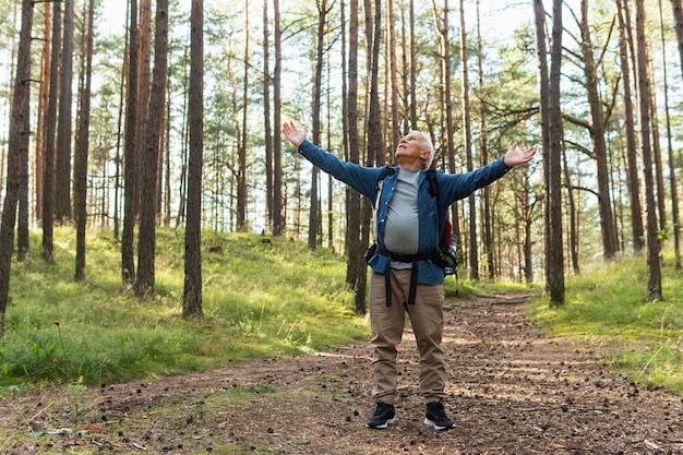 Feliz anciano con los brazos abiertos en la naturaleza