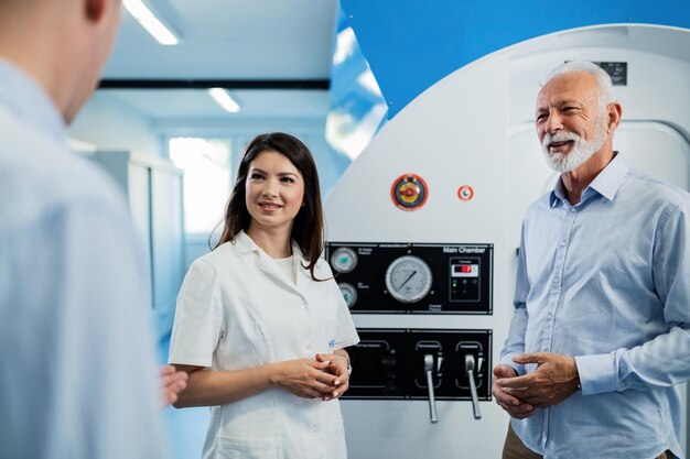 Feliz anciano y doctora hablando con un paciente irreconocible sobre la experiencia de la oxigenoterapia en cámara hiperbárica