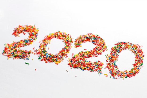 Feliz año nuevo 2020. Forma de número colorido con chispitas de azúcar de arco iris brillante aislado en blanco