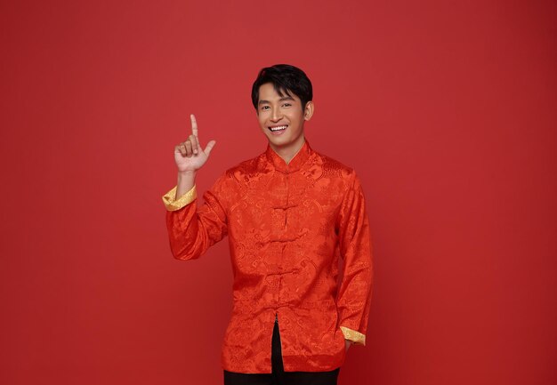 Feliz año nuevo chino 2024 hombre asiático con traje tradicional rojo y manos apuntando con el dedo hacia arriba
