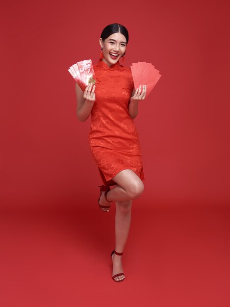 Feliz año nuevo chino mujer asiática con vestido tradicional cheongsam qipao sosteniendo angpao