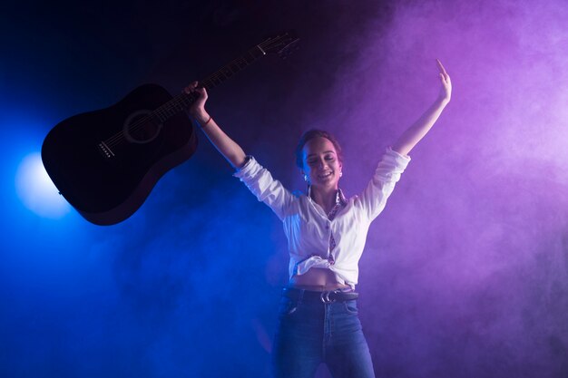 Feliz artista en el escenario sosteniendo la guitarra