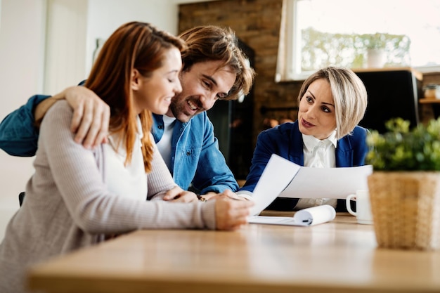 Feliz asesor financiero consultando con una pareja joven en su casa.