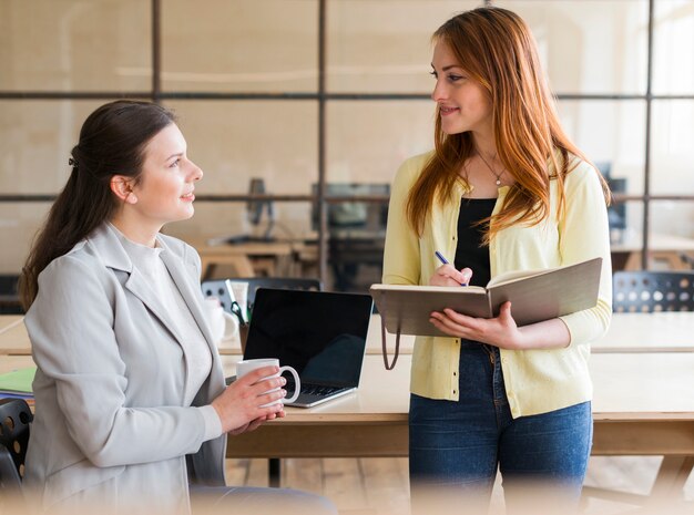 Feliz atractiva mujer dos trabajando juntos en el lugar de trabajo