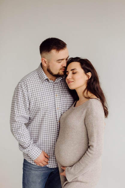 Feliz y atractiva mujer embarazada y su marido posando en el estudio