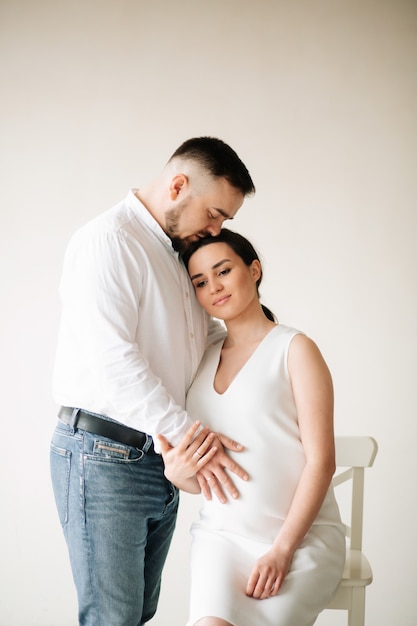 Feliz y atractiva mujer embarazada y su marido posando en el estudio