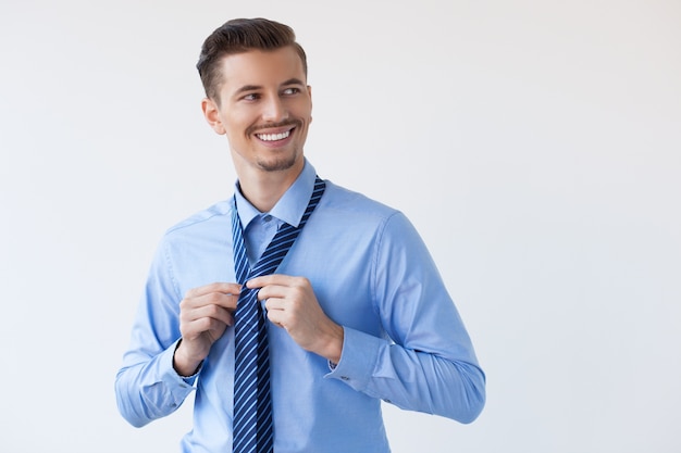 Feliz atractivo elegante del hombre joven que ata la corbata