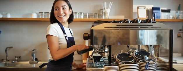 Foto gratuita feliz barman sonriente barista usando la máquina de café preparar el pedido haciendo capuchino o latte