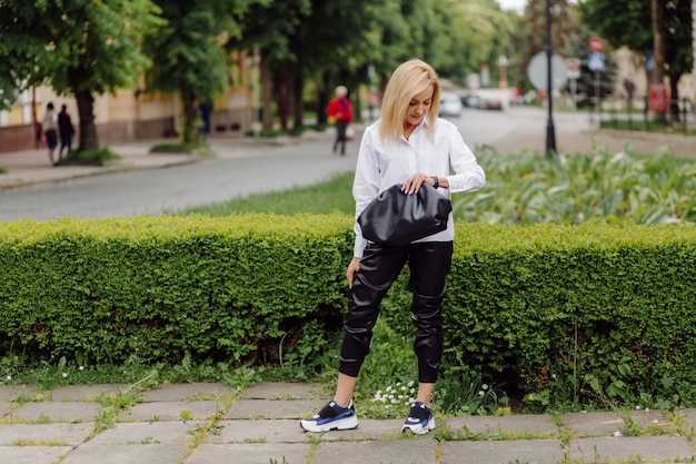 Feliz bella mujer joven usando su teléfono inteligente caminando por la calle de la ciudad