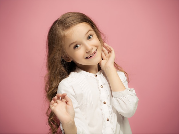 Feliz chica adolescente de pie, sonriendo aislado en la pared rosa de moda. Hermoso retrato femenino. Chica joven satisface. Las emociones humanas, el concepto de expresión facial. Vista frontal.